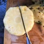 a knife cutting down beside the core of a pineapple