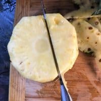 a knife cutting down beside the core of a pineapple