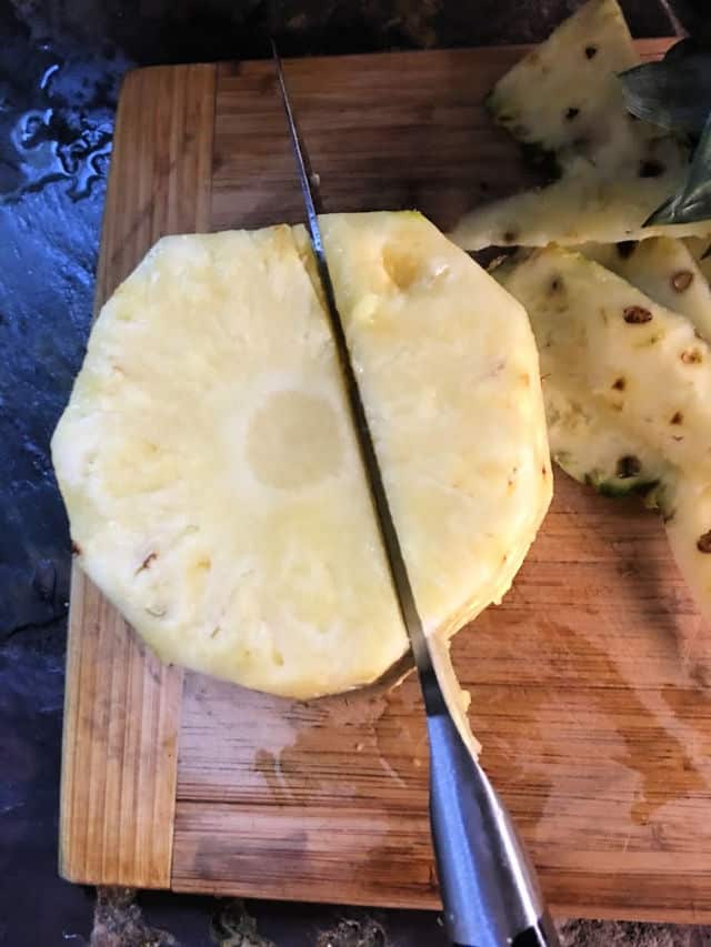 a knife cutting down beside the core of a pineapple