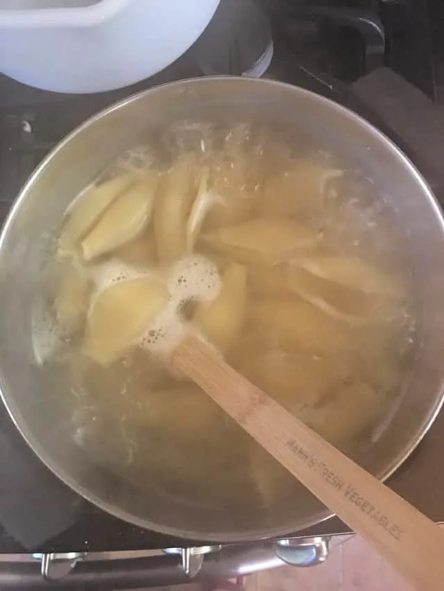 Jumbo Pasta Shells cooking in stockpot with wooden spoon