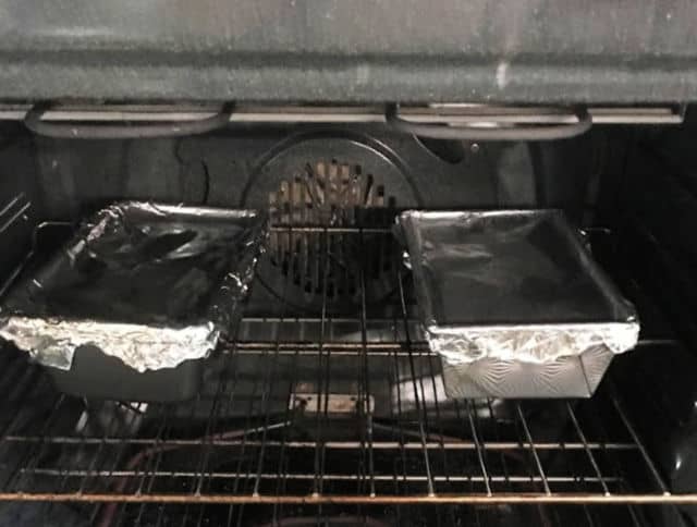 two bread pans covered with aluminum foil in the oven to make southern meatloaf recipe