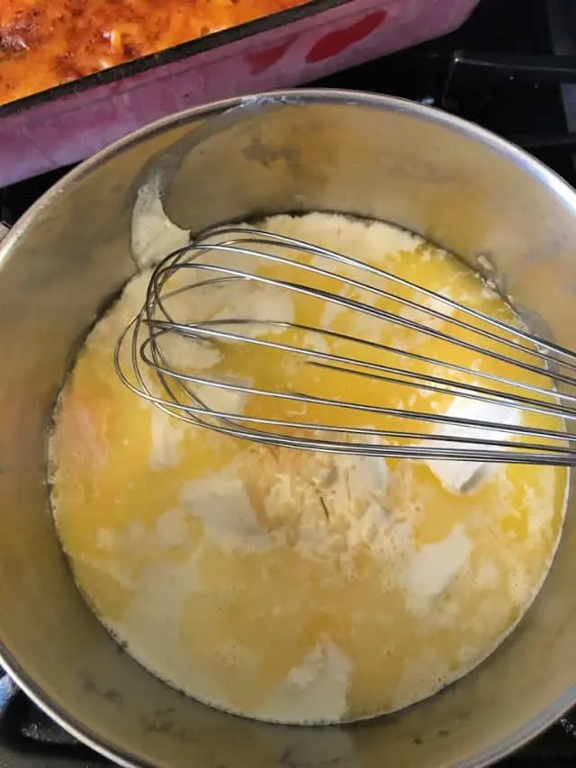 using a whisk to stir the cheese sauce
