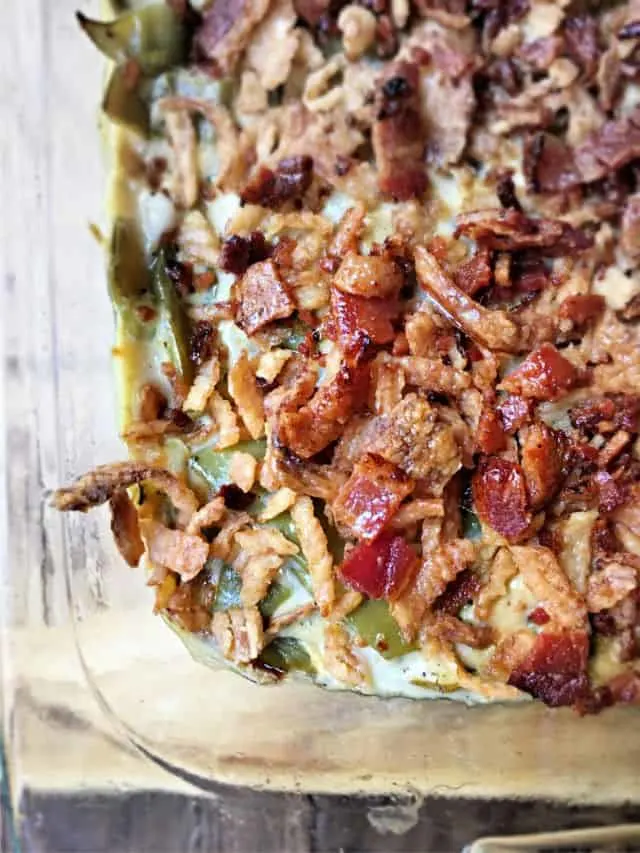 close up corner of green bean casserole with large pieces of bacon