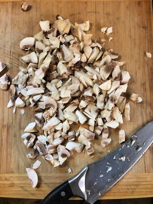 Chopped mushrooms on a cutting board with knife