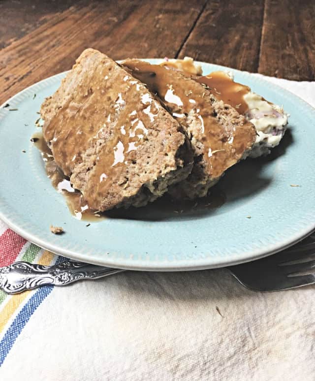 blue plate with meat loaf covered with brown gravy