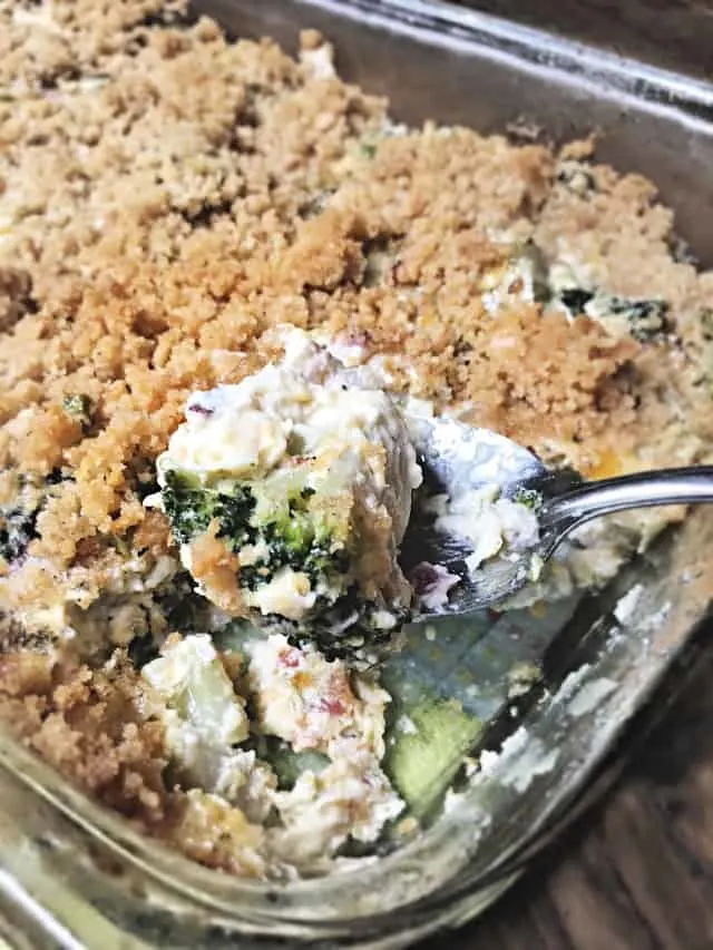 a tablespoon holding up a bite of broccoli casserole