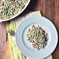 pea salad on a blue plate with fork and green towel