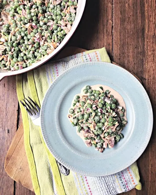 pea salad on a blue plate with fork and green towel