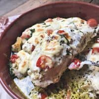 piece of chicken being lifted from baking dish