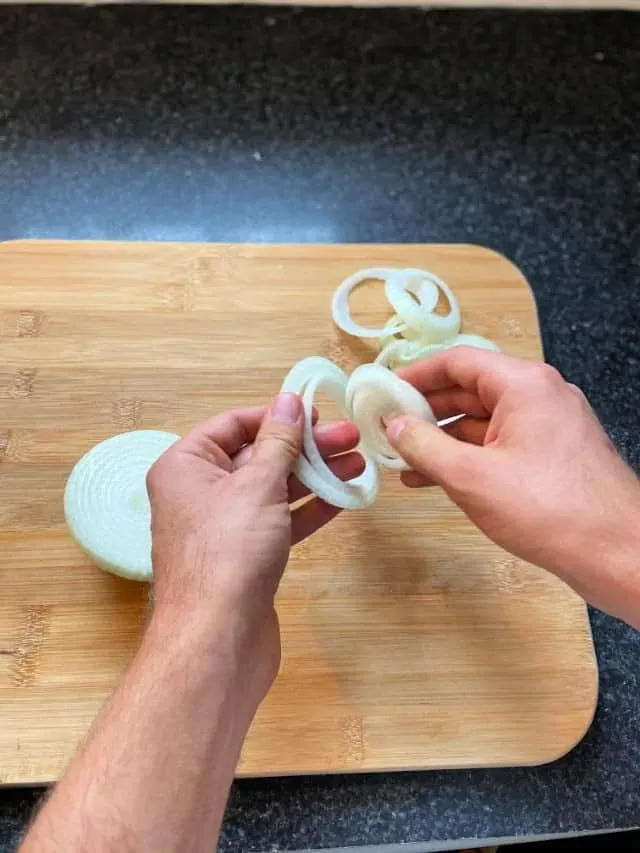 two hands separating the onion into rings