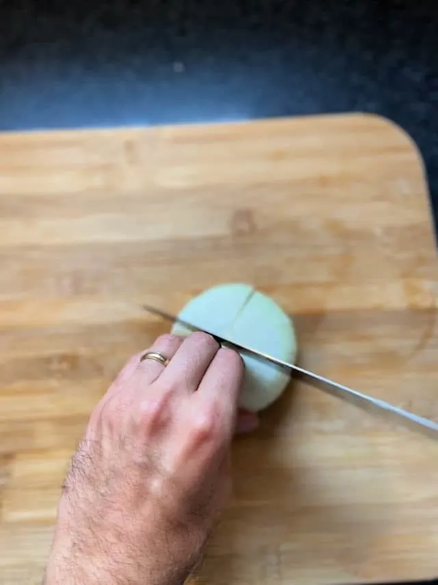 hand holding onion still on cutting board