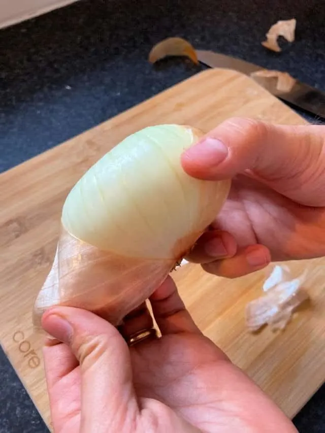 hand holding and onion pulling the peel off