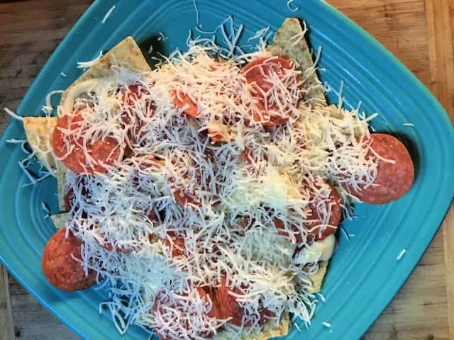 shredded cheese sprinkled over the top of the nachos on blue plate