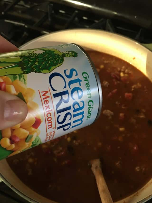 can of mexi corn being added to stockpot of soup