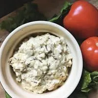 white bowl of coleslaw with tomato and lettuce in background