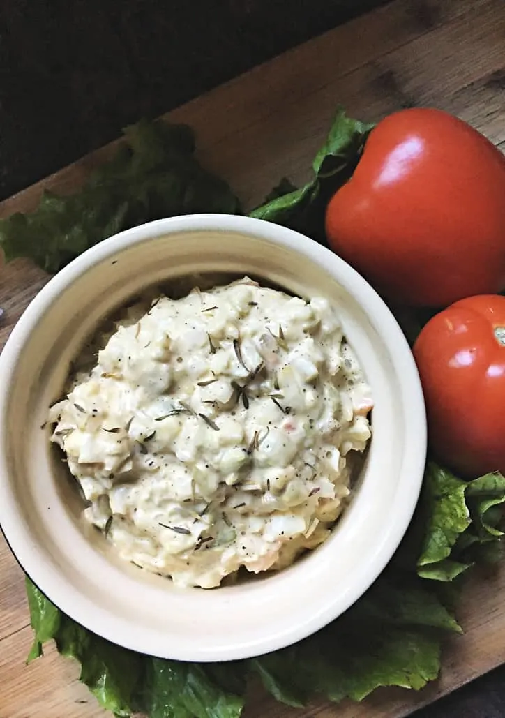 white bowl of coleslaw with tomato and lettuce in background