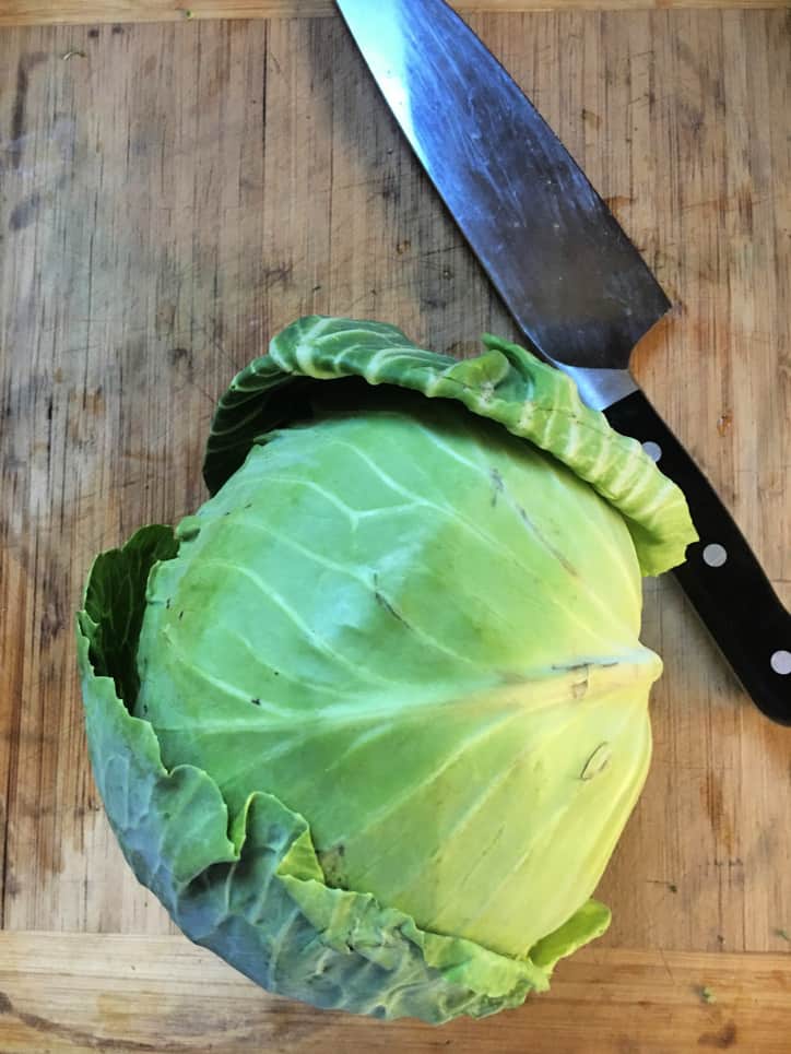 head of cabbage and knife on cutting board