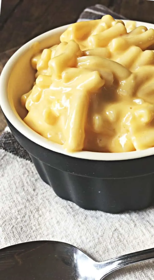 close up of mac and cheese in black bowl with towel