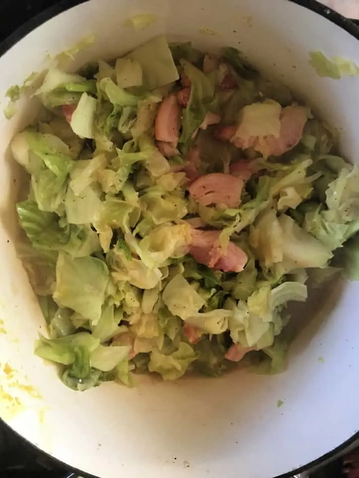 southern fried cabbage recipe cooked up in stock pot with bacon visible