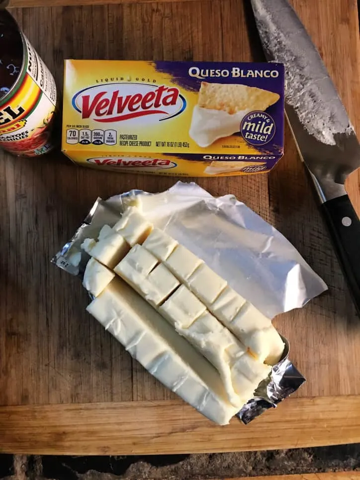box of velveeta queso blanco, knife, rotel can, block of cheese cut into cubes