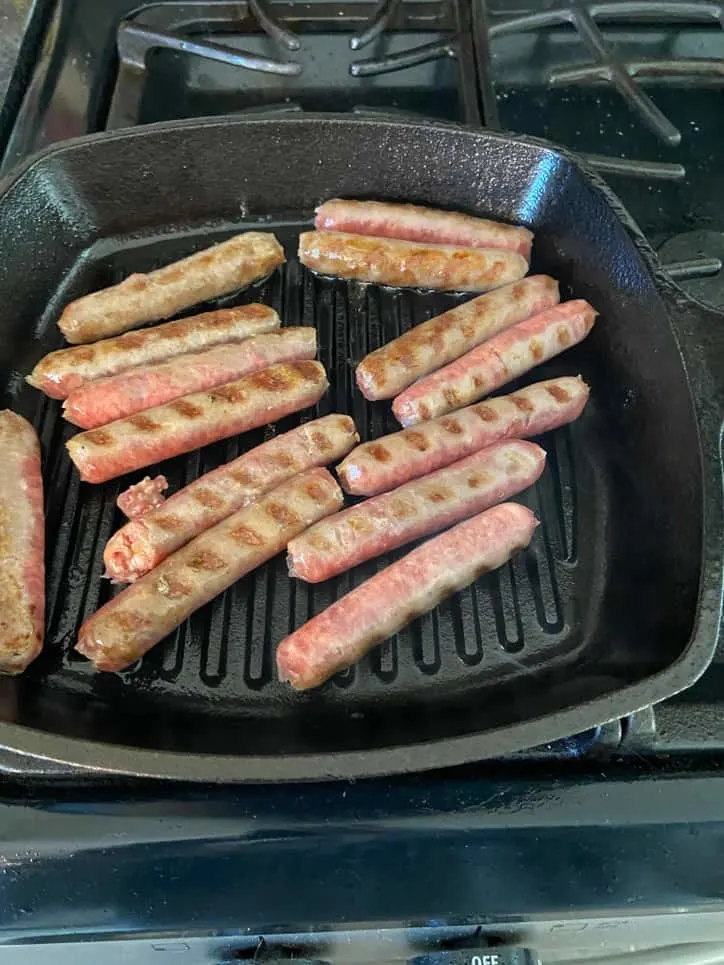 sausage links with grill marks on black pan on stove