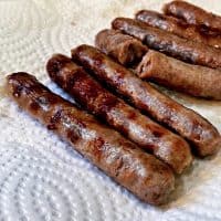 browned sausage links with grill marks on paper towel.