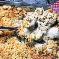 wooden spoon dipping out some easy chicken and rice casserole from glass pan