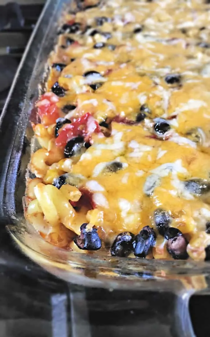 cheesy beans and macaroni in the corner of a glass casserole dish