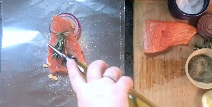 piece of salmon with hand pouring oil on top