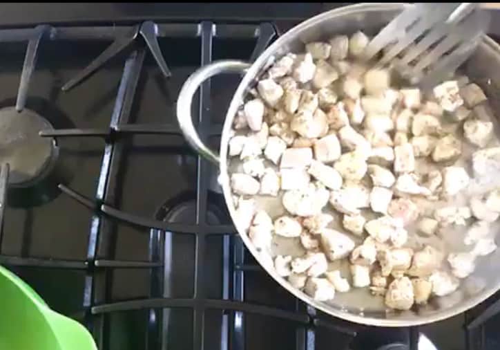 frying pan of chicken pieces cooking on the stove top