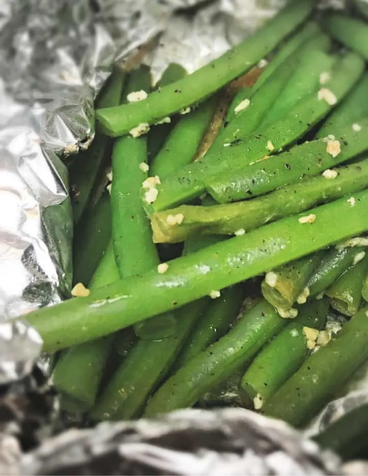 fresh green beans roasted in aluminum foil on the grill