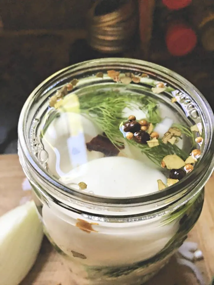 looking into the top of jar of pickled eggs with spices floating