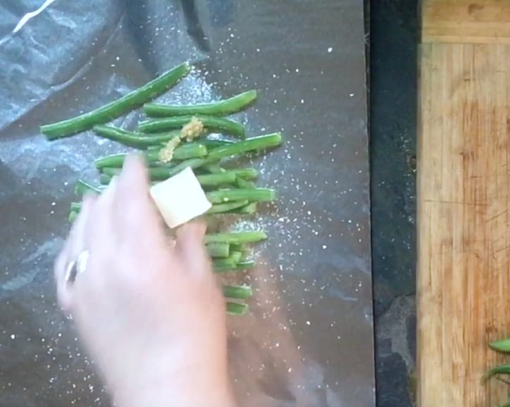 hand adding a pat of butter on foil
