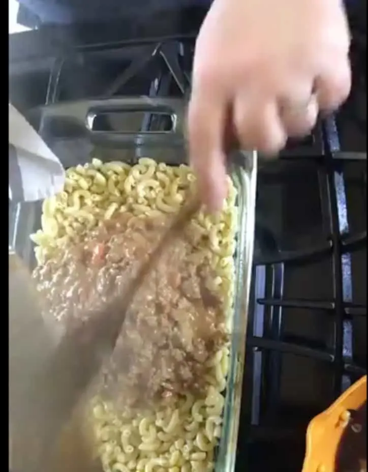 ground beef and cheese added over the top of macaroni noodles in pan