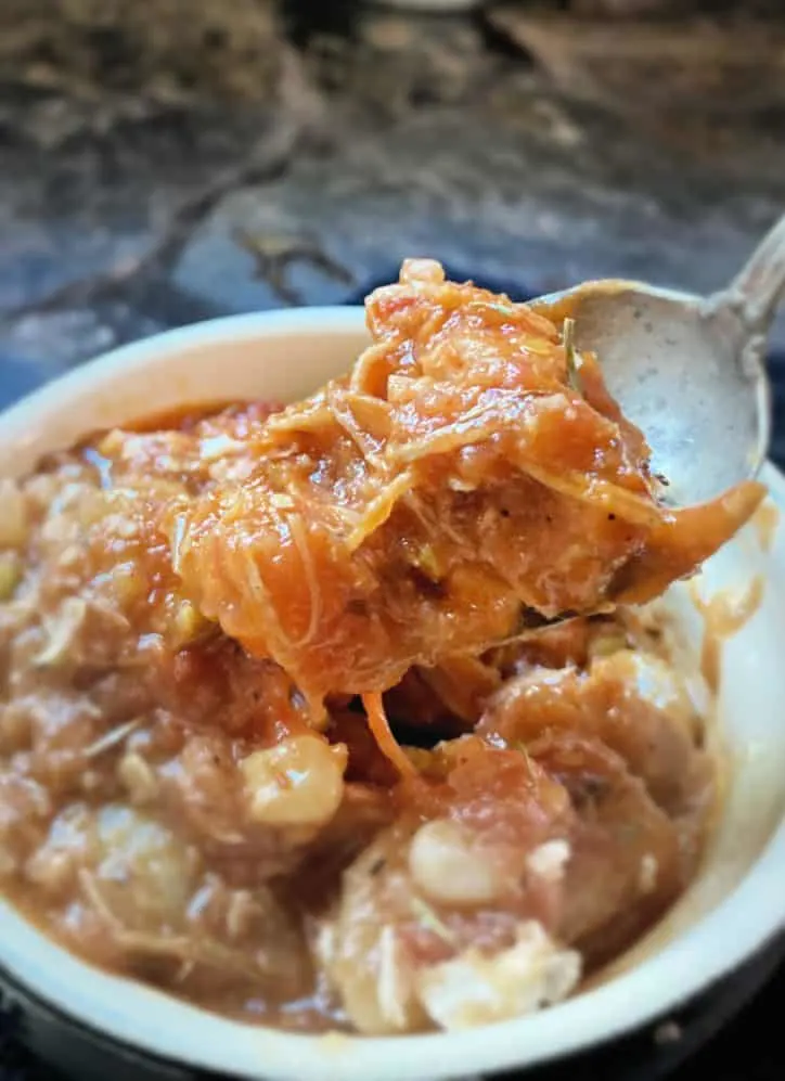 Spoon full of rich and thick brunswick stew over the small bowl of stew