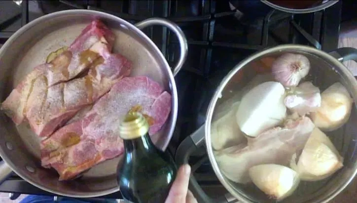 olive oil being poured over pork in a pan