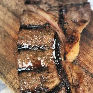 glistening steak on cutting board with grill marks