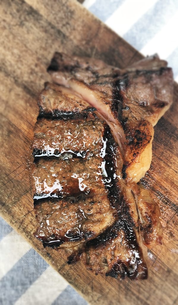 glistening steak on cutting board with grill marks