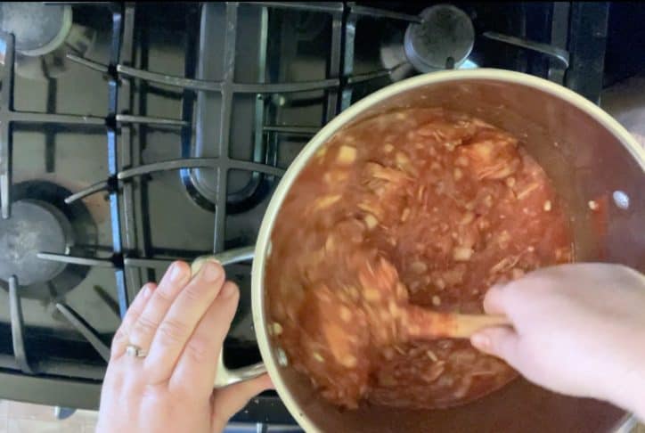 hand mixing nc brunswick stew with wooden spoon