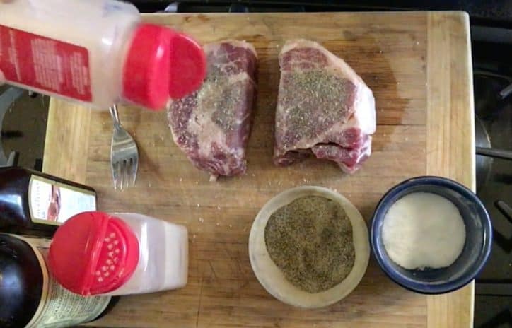 two raw steaks on cutting board with spices