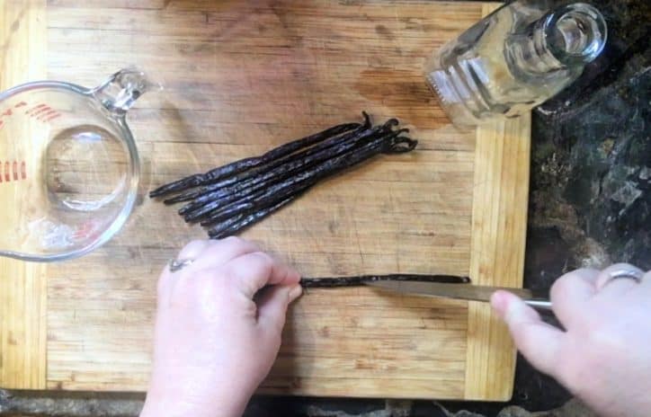 two hands cutting vanilla beans