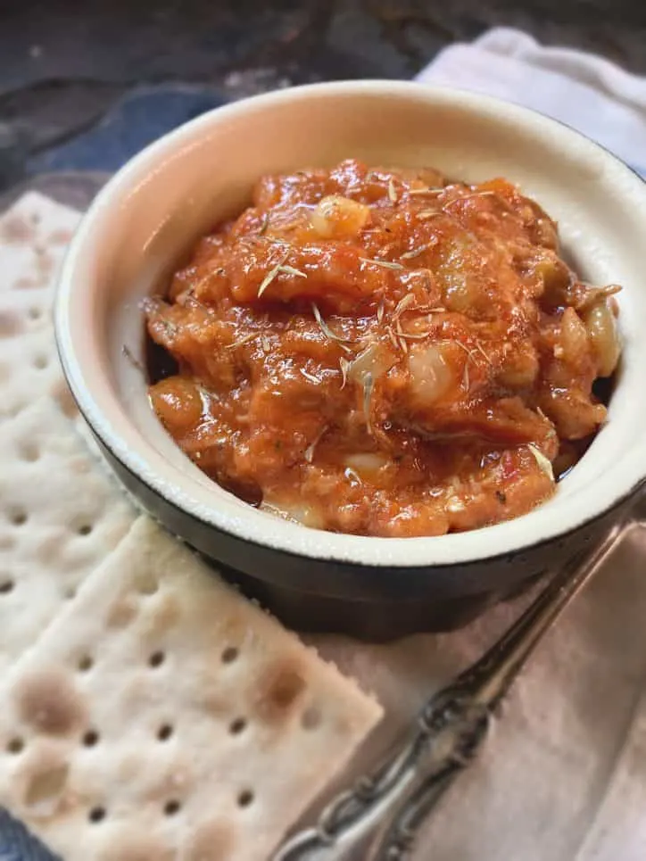 side view of stew in bowl with saltines and spoon handle