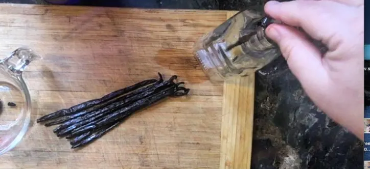 hand placing bean pods in bottle