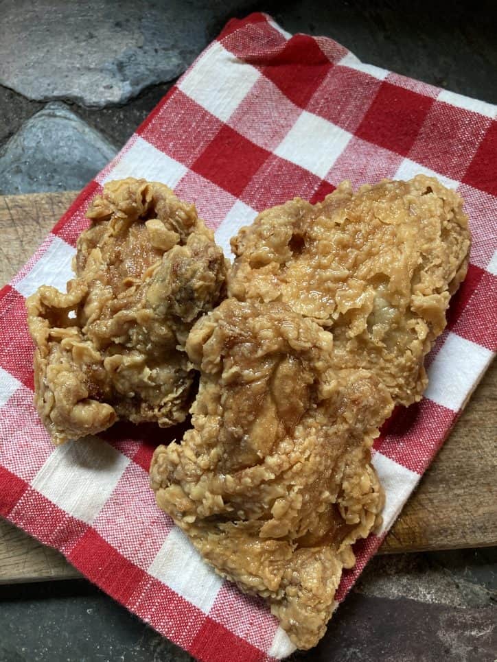 three pieces of fried chicken on red checkered napkin