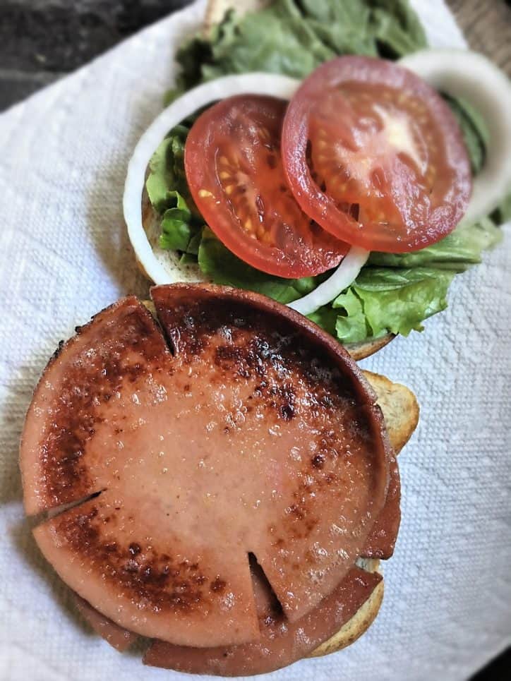 slice of fried meat on a sandwich with tomato onion and lettuce