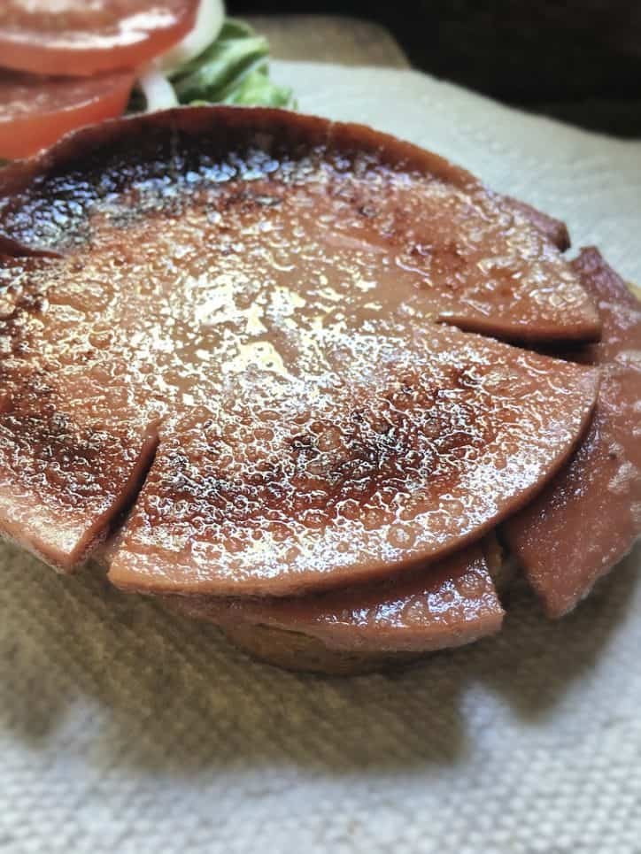 two slices of fried bologna on a paper towel