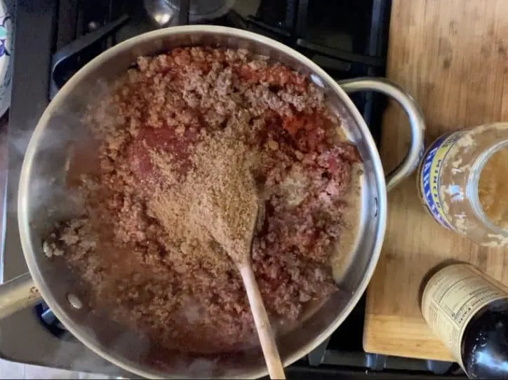 browned hamburger with other ingredients and wooden spoon