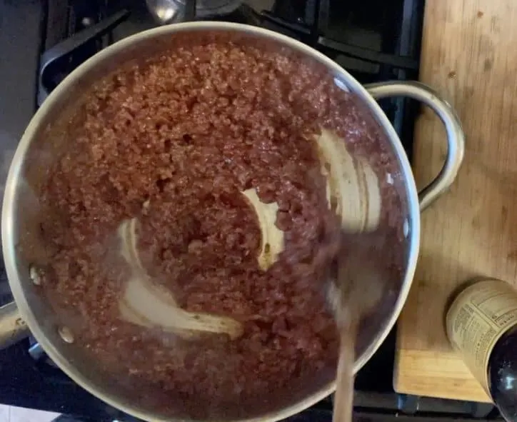 spoon mixing ground beef and other ingredients in pan