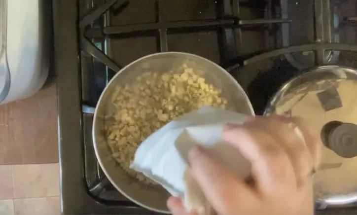 hand adding stuffing mix package to sauce pan