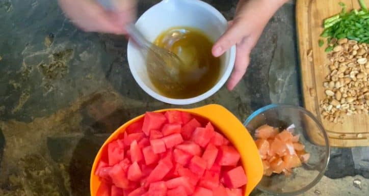 hand mixing dressing ingredients in white bowl